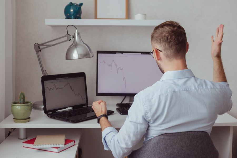 Forex trader getting angry and frustrated sitting in front of his workstation screen