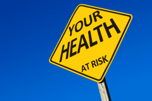 Yellow diamond road sign with sky blue background saying Your Health is at Risk.